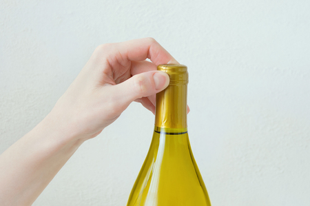 Hand caucasian girl opens a bottle of wine. Close-up. White background.の写真素材