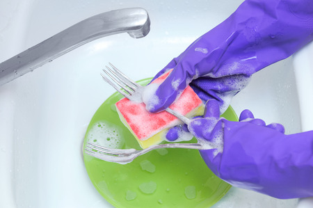 Washing dishes with a sponge cleanser. Hands in protective rubber gloves.の写真素材