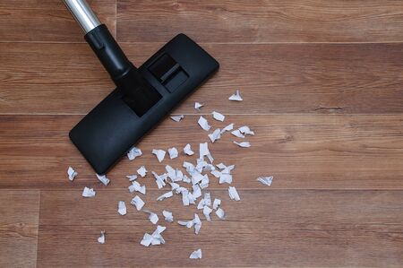 House cleaning. Collecting paper trash vacuum cleaner on wooden brown floor.の写真素材