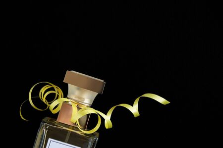 Glass golden bottles with perfume and serpentine ribbon on a black background. View from above.の写真素材