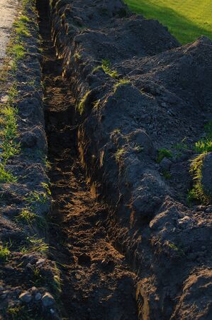 Dug in the ground trench for the pipeline. In the evening on the city street.の写真素材
