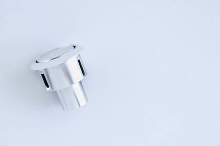 Chrome button for flushing the toilet bowl on a white background.
