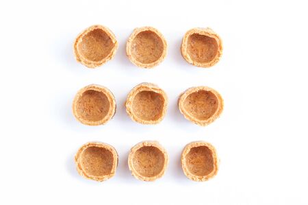 Indian sweets. Small yellow coconut tartlets on a white background.