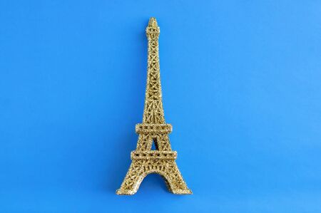 Golden shiny eiffel tower figurine on a blue background.の写真素材