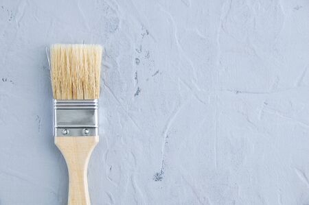 Painting new brush with a wooden handle on a gray concrete background.