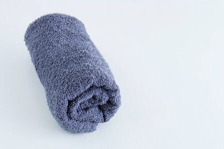 Gray terry towel folded into a roll on a white background.の写真素材