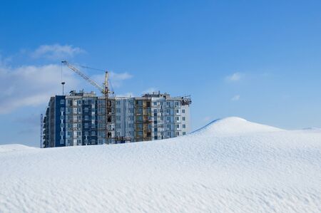 Under construction multi-storey building on a background of a snowdrift in the winter afternoon.の写真素材
