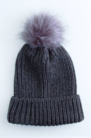 Woolen dark gray hat with a fur pompom on a white background.の写真素材