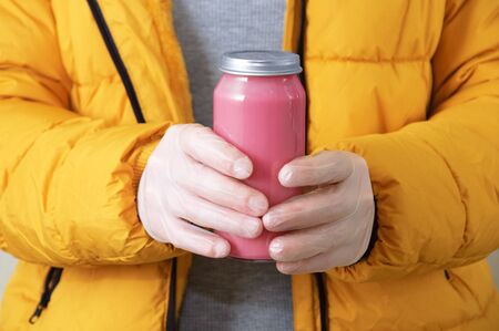 Jar with mashed berry in a girl with protective gloves on her hands close-up.の写真素材