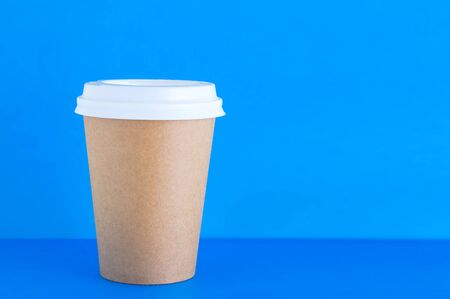 Paper brown cup of coffee close-up on a blue background.の写真素材