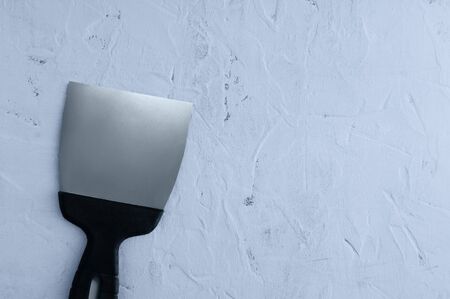 Metal spatula scraper with black handle on a gray concrete background. View from above.の写真素材