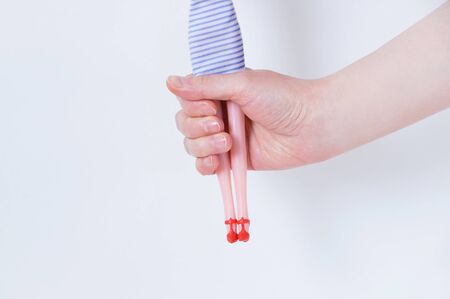 Toy doll in the hands of a caucasian girl close-up on a white background.の写真素材