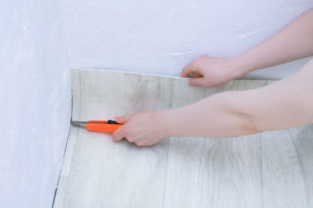 Caucasian woman cuts linoleum on the floor. Linoleum laying. Repair and home improvement.の写真素材