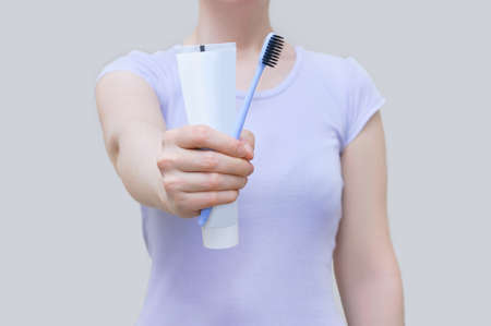 Morning hygiene. Close-up of toothbrush and paste in the hands of Caucasian woman.