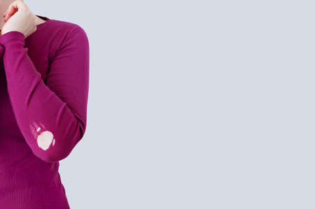 Caucasian woman in purple clothes with holes on the elbow. White background. Place for your text.の写真素材