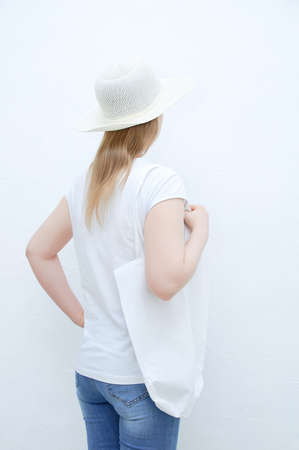Zero waste concept. Caucasian young woman with her back in a white t-shirt with a cotton bag on her shoulder.の写真素材