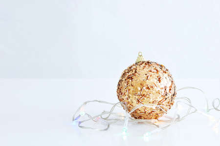 Christmas gold glittering ball and glowing garland close-up.