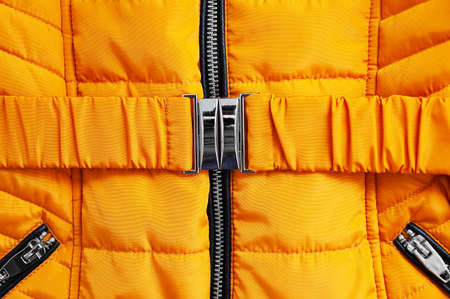 Metal fastener belt close-up on a yellow down jacket.