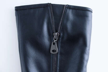 Zipper metal lock on a black leather boot close-up. White background.