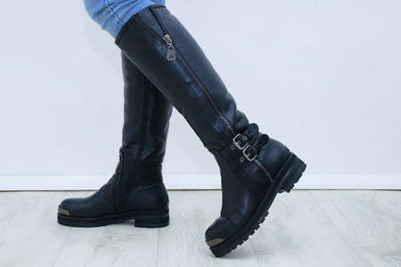 Black boots with metal fasteners on the woman legs.