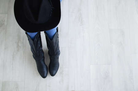 Woman legs in black cowboy boots with cowboy hat close-up.の写真素材