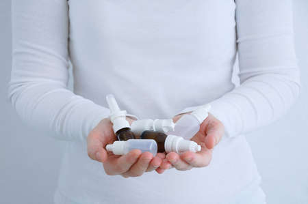 Bottles with nasal drops in the hands of a Caucasian woman close up.