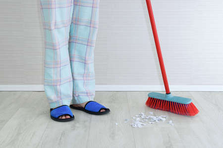 Caucasian woman housewife sweeping the floor with a brush.の写真素材