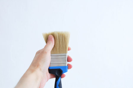 Paint brush in hand. He touches the bristles of the brush with his finger.