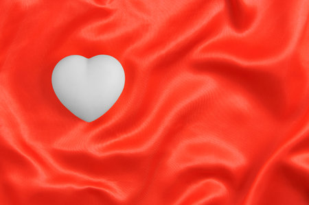 White heart on red satin fabric. Valentines Day.の写真素材