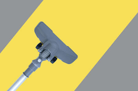 Gray vacuum cleaner with a floor nozzle on a yellow-gray striped background.