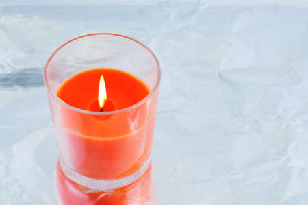 Burning orange aroma candle close-up in a glass on a metallic gray background. View from above.の写真素材
