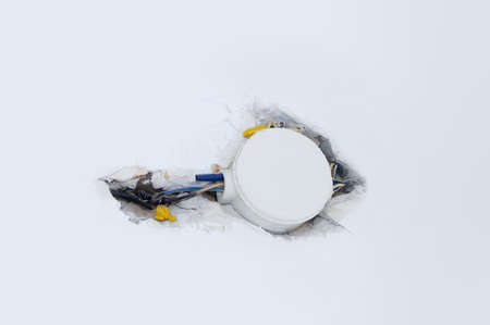 Electrical damaged wiring on a white wall close-up.