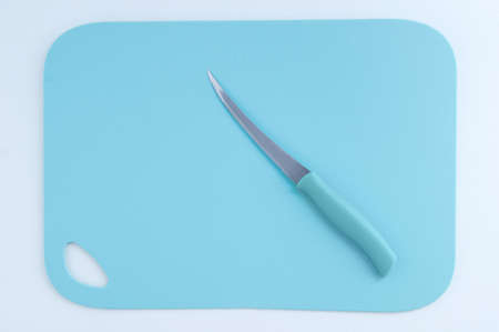 Kitchen turquoise plastic cutting board and knife. White background.