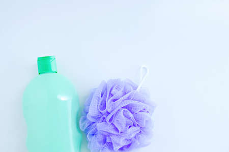 Purple nylon body scrubber and bottle of shower gel close-up on a white background.の写真素材