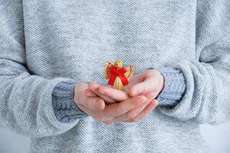 Straw angel in the hands of a caucasian woman close up.
