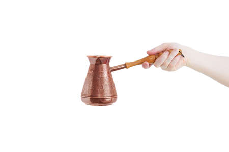 Coffee bronze turk for making coffee in the hand of a Caucasian woman. White isolate.の写真素材
