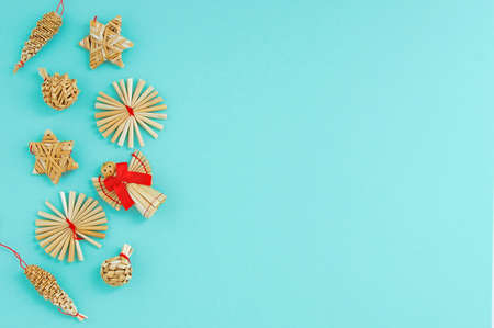 Christmas decoration made of straw and a figurine of an angel with a red bow on a turquoise background. Place for your text.の写真素材