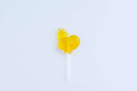 Yellow candy cane lollipop in the shape of a rooster on a white background.の写真素材