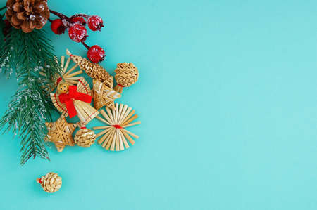 Christmas straw angel with a red bow and straw decorations on a branch of a Christmas tree....