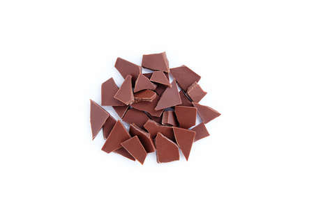 Broken pieces of milk chocolate in a bunch on a white background.