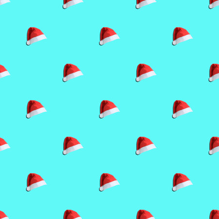 Red Santa hats with a pompom on a turquoise background. Seamless pattern.の写真素材