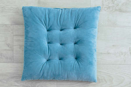 Soft turquoise chair seat cushion on white wooden background.の写真素材