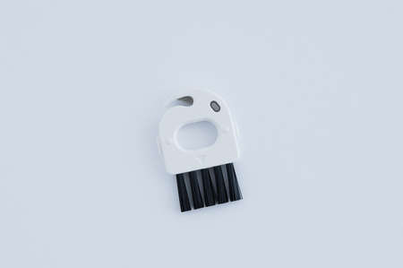 Small brush for removing dirt for a robot vacuum cleaner. White background.