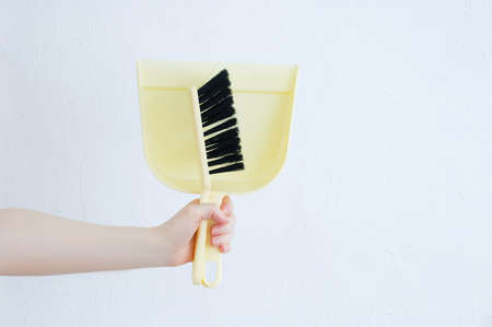 Brush and scoop in the hand of a Caucasian woman close up. White background.の写真素材
