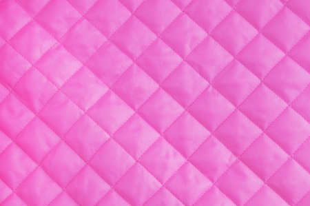 Pink quilted lining fabric background texture close-up.の写真素材