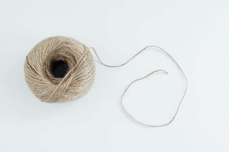 A skein of brown twine with a loose thread on a white background. A ball of jute twine. View from above.の写真素材