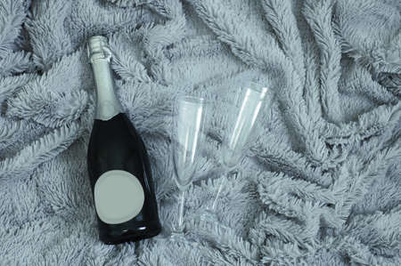 A bottle of champagne and two glasses against the background of a gray fur plaid.の写真素材