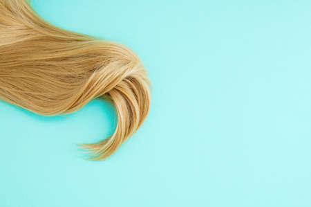 golden blond strand hair. green background. Place for text.の写真素材