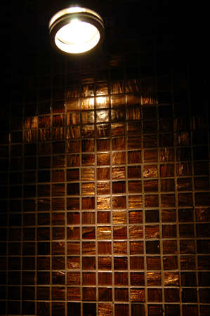 Lamp on the background of a brown shiny wall with ceramic mosaic tiles.の写真素材