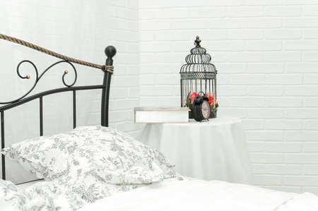 Decor in the bedroom. Metal bed and decorative cage on the table.
